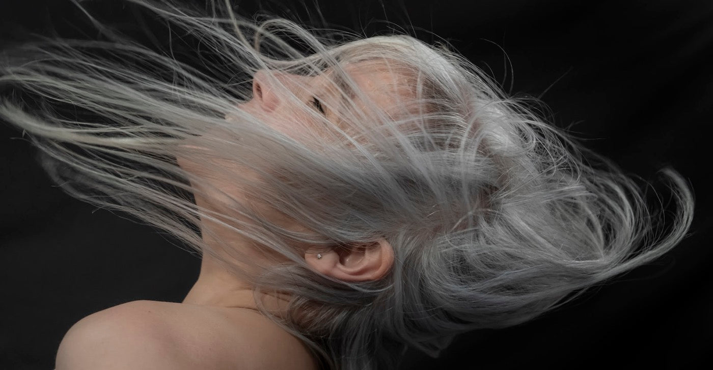 Silver hair in motion against a dark background